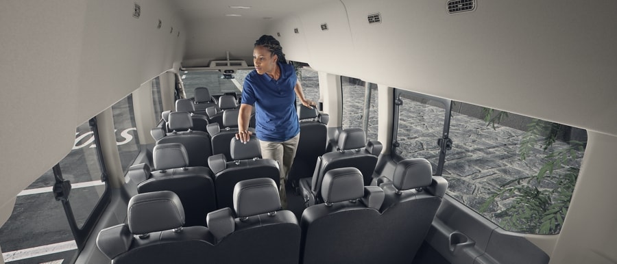 A woman standing inside a 2023 Ford Transit® van with 15 seats