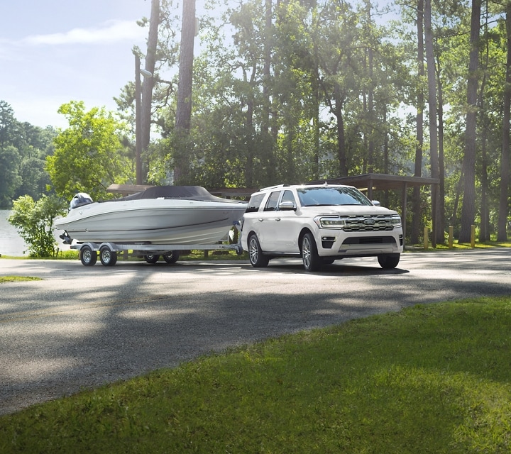 A 2024 Expedition Platinum Max model towing a boat from a boat launch